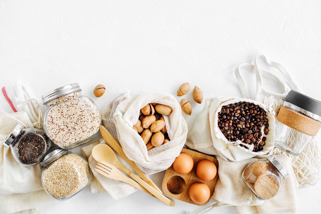 Nuts, dried fruits and groats in eco cotton bags and glass jars on white table in the kitchen. Zero Waste Food Shopping. Waste-free living