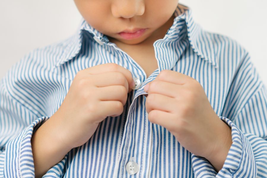 Close up of a little kindergarten boy's hands learning to get dressed