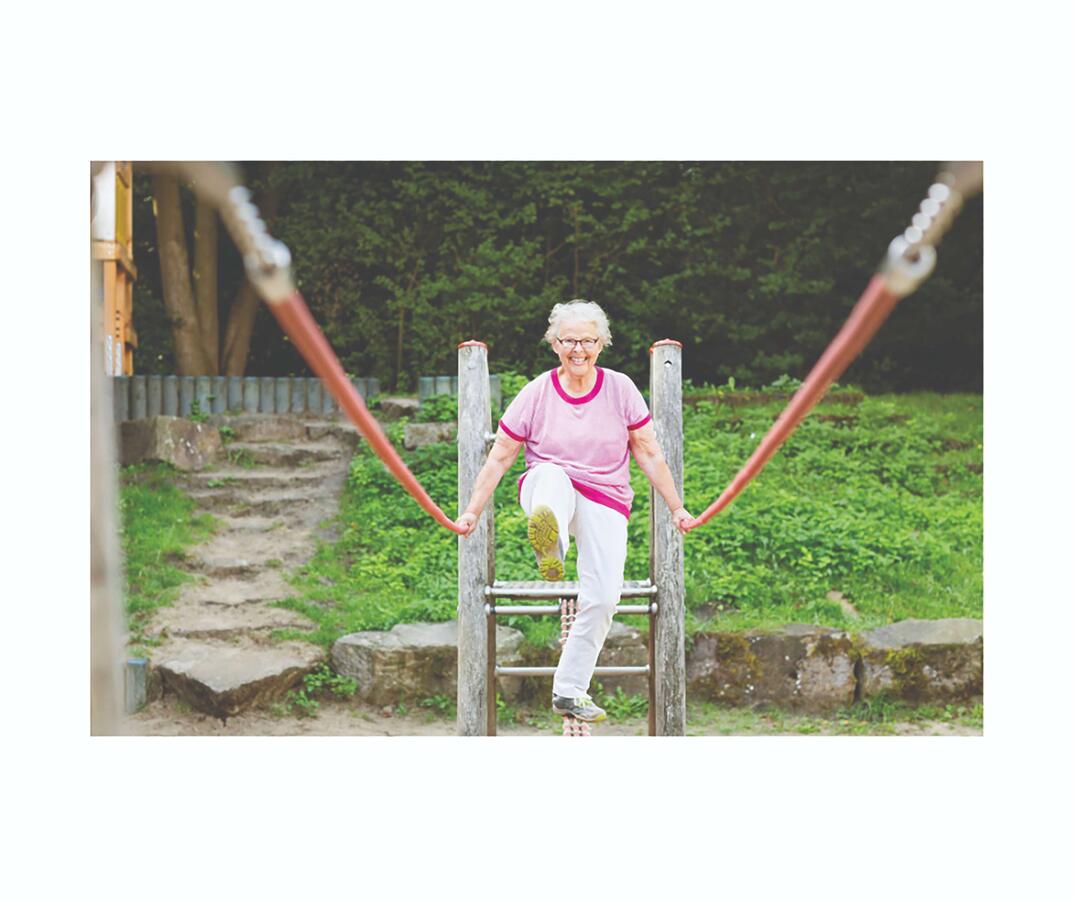 Older woman walking across a rope bridge