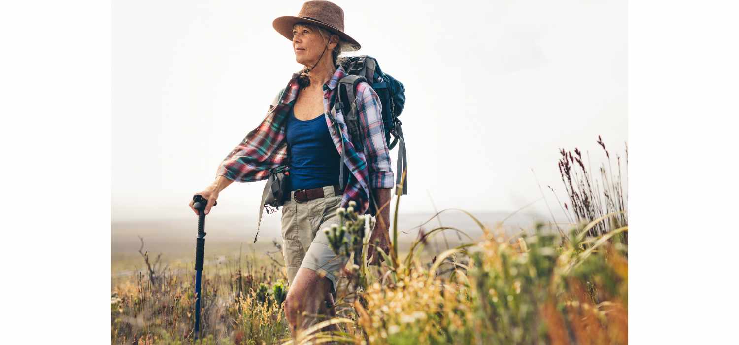 Senior woman on a hiking trip with the help of a trekking pole.