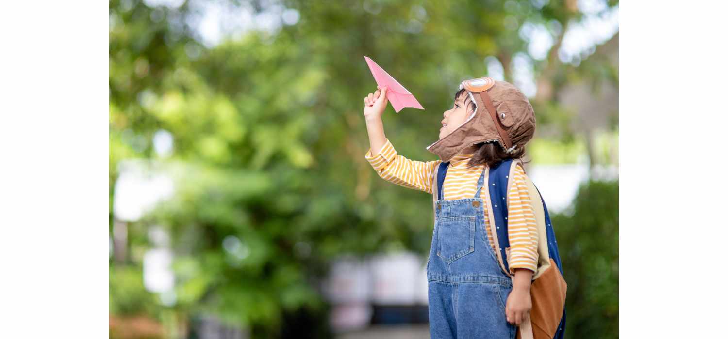 Little boy flying a paper airplane