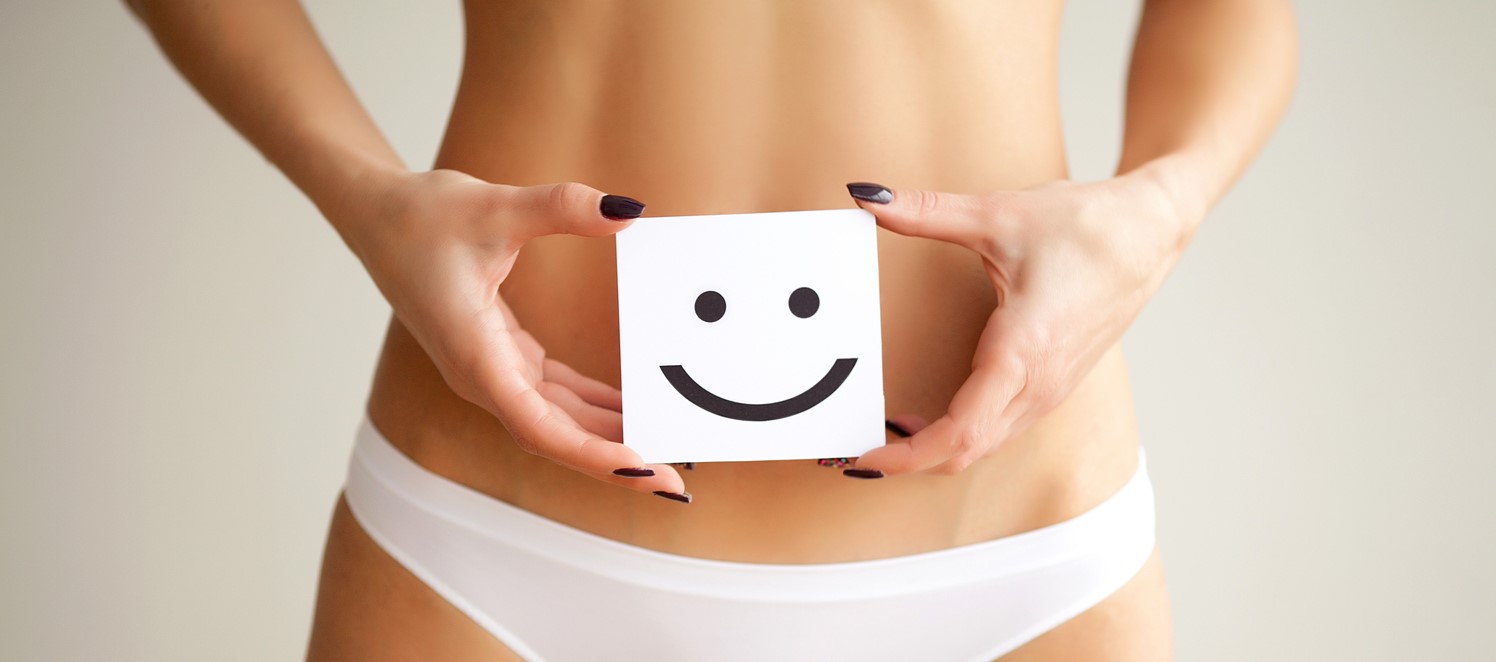Woman holding paper with smile mark over her stomach