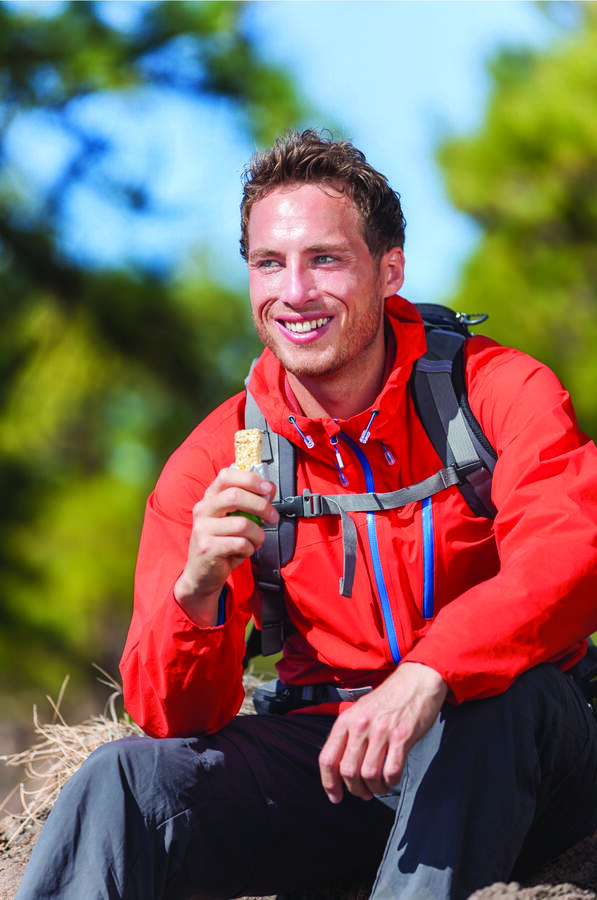 A man smiling as he holds up his food bar, clearly enjoying the moment