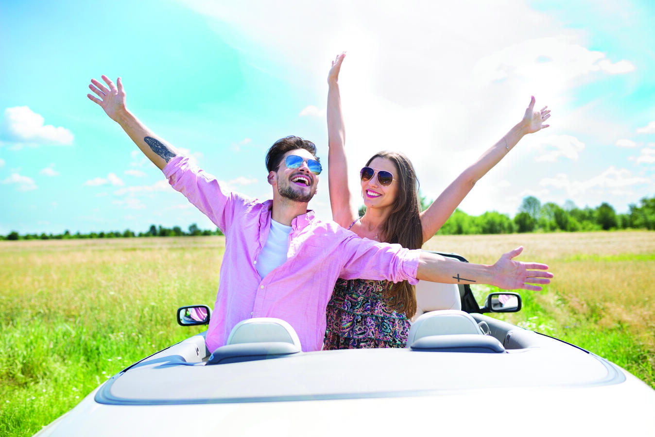 A man and a woman standing side by side, arms outstretched
