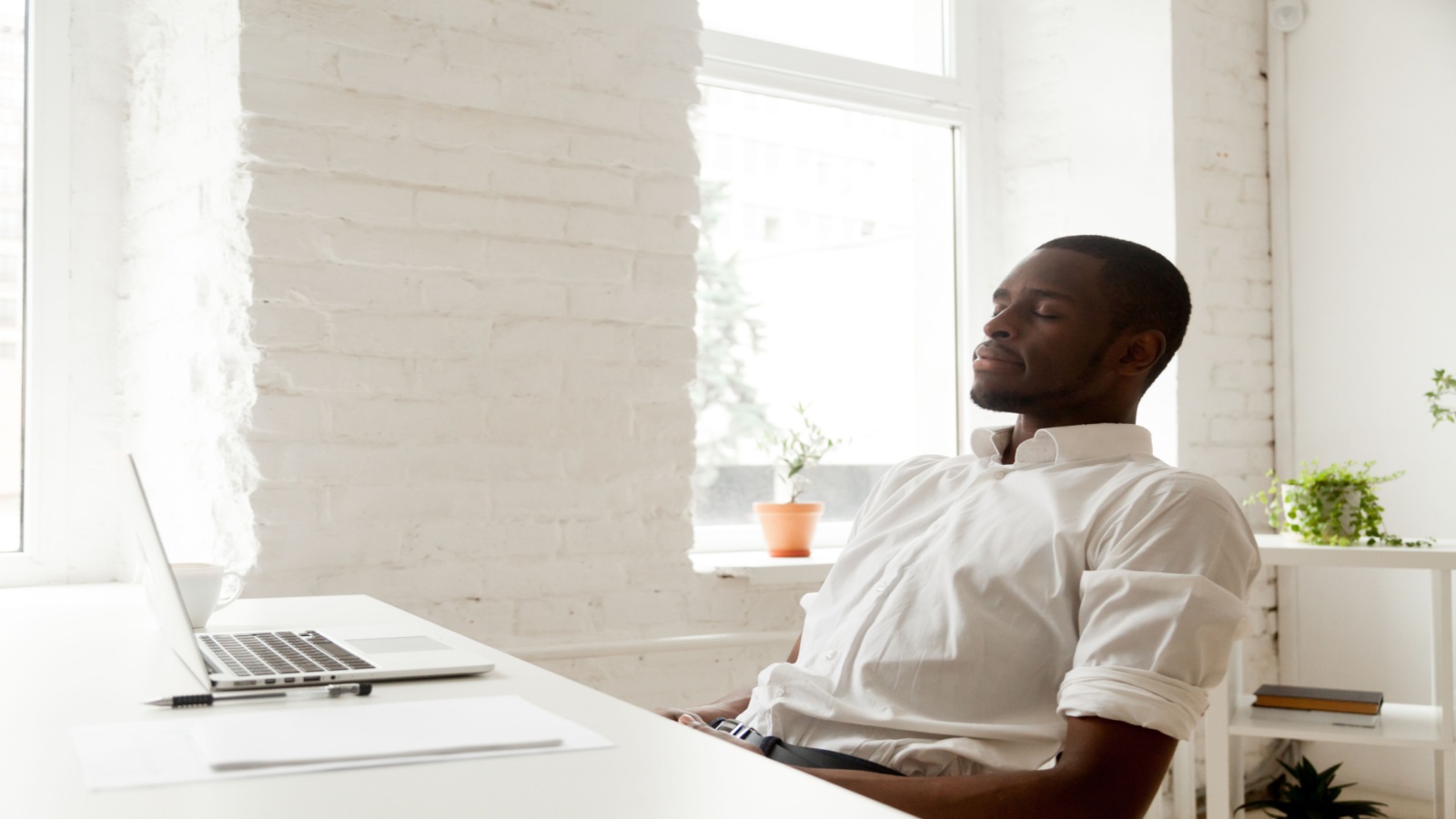 man meditating at his desk in front of the computer