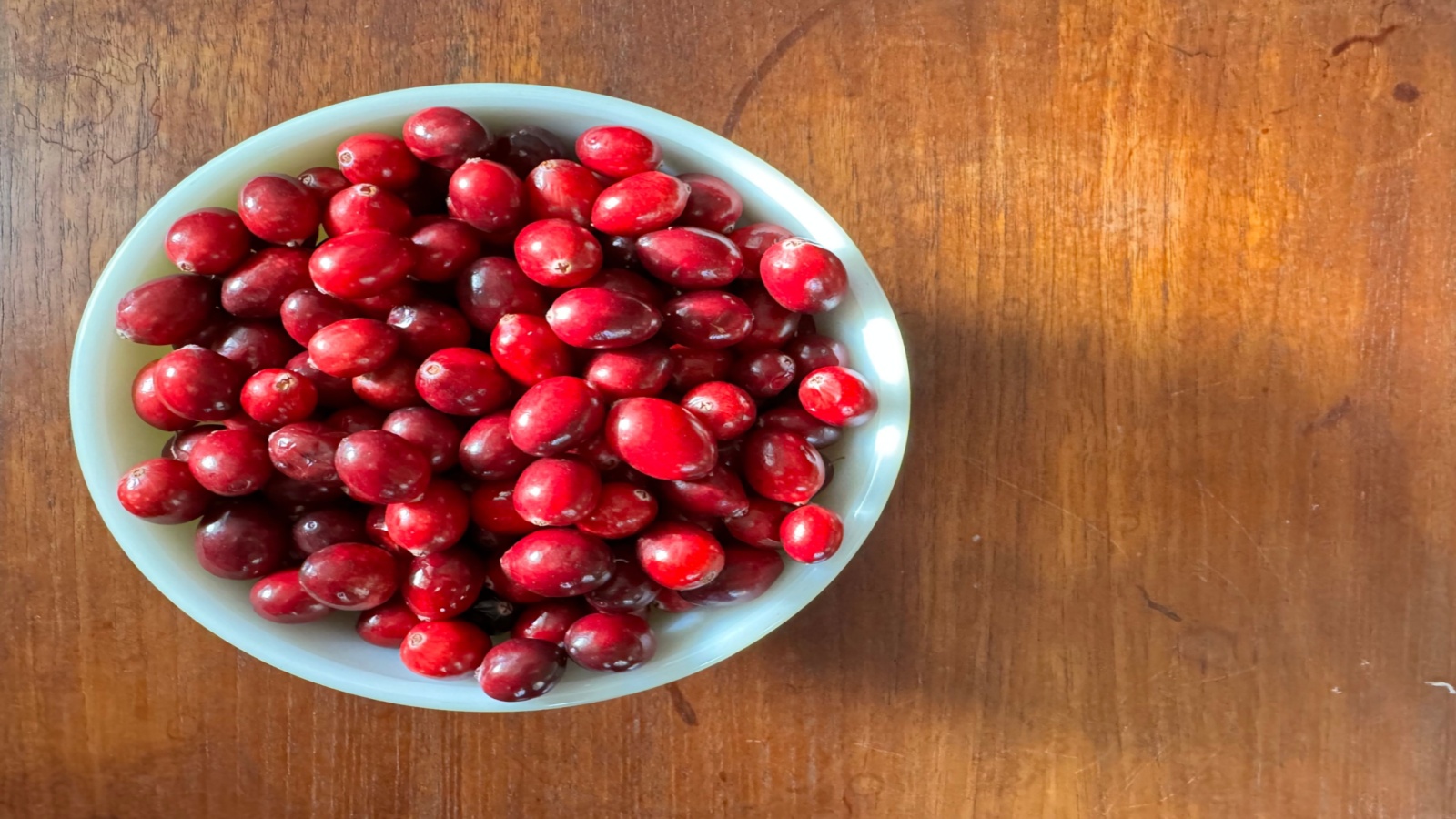 Fresh cranberries in a bowl on top of a wooden table