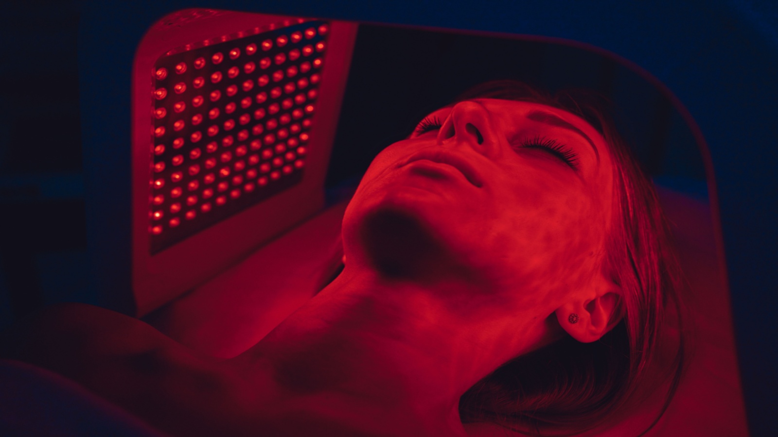 LED red light is treating the facial skin of a young woman. 