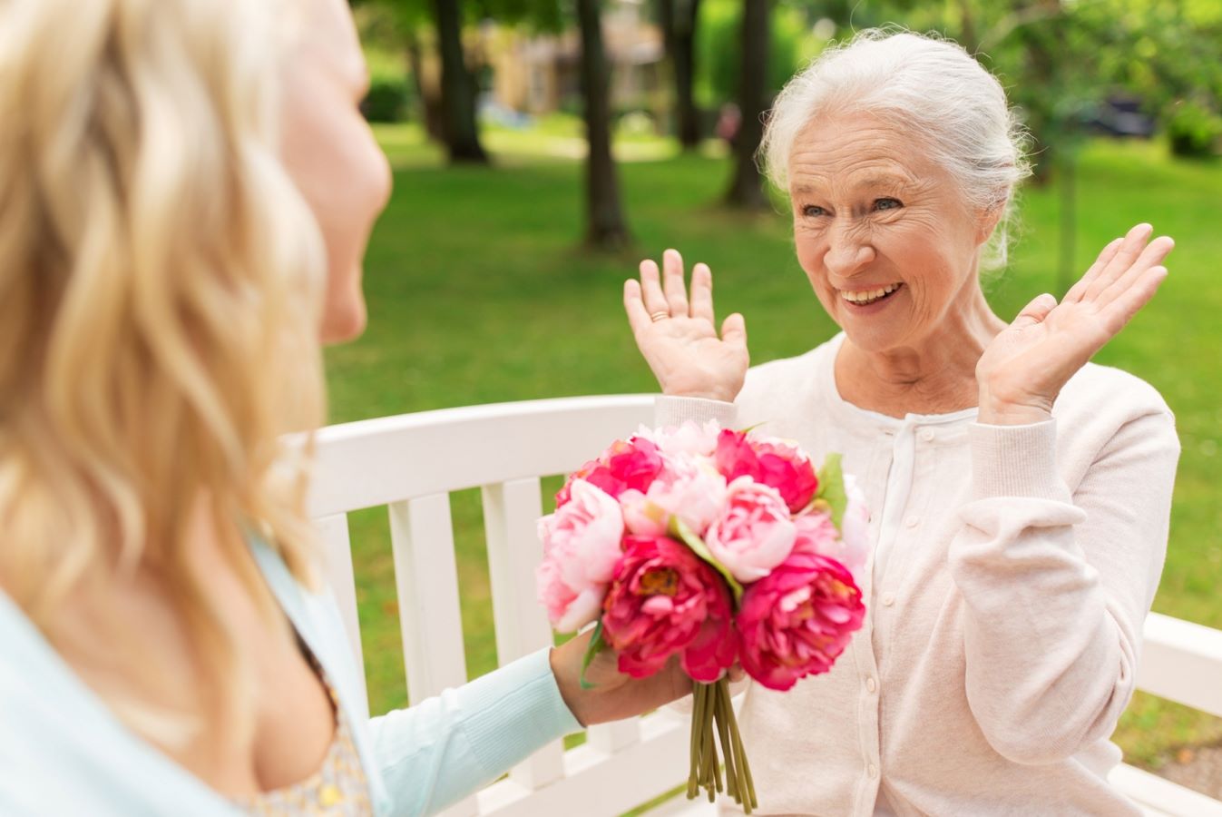 Woman presenting bouquet of flowers to older woman