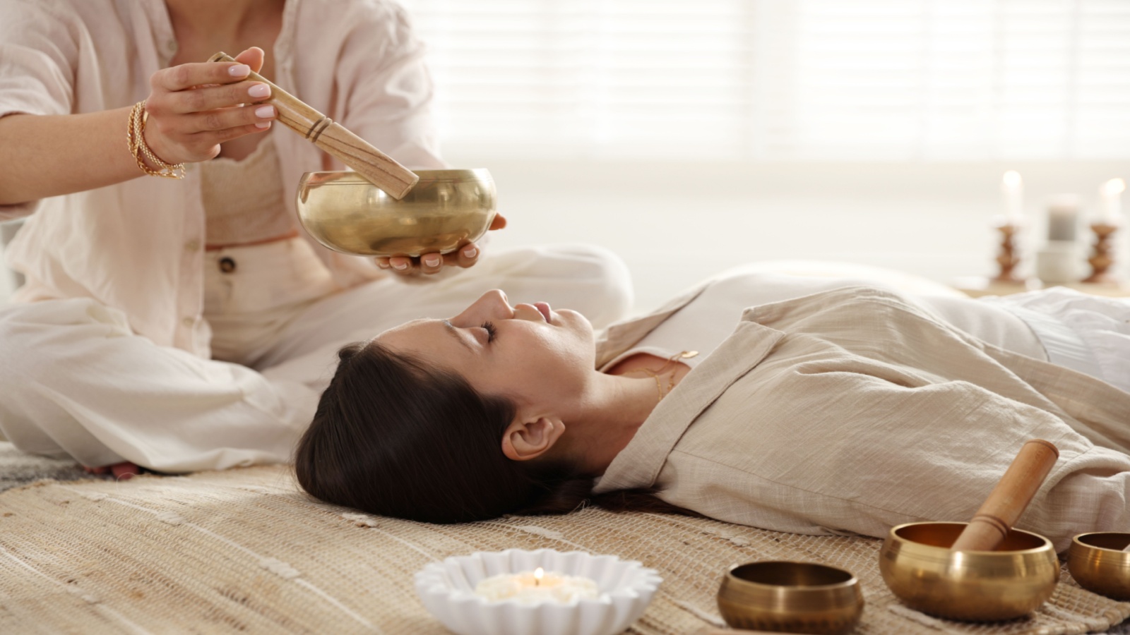 woman receives sound bath from singing bowls, which are different than Biofield Tuning methods