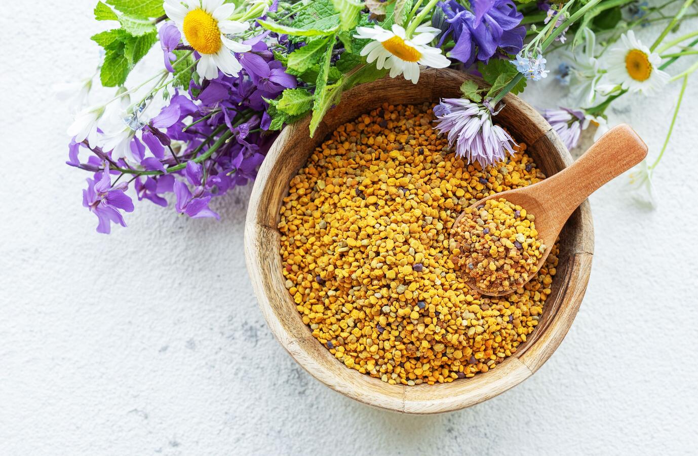 Bee pollen (not propolis) in a bowl with purple and white wildflowers