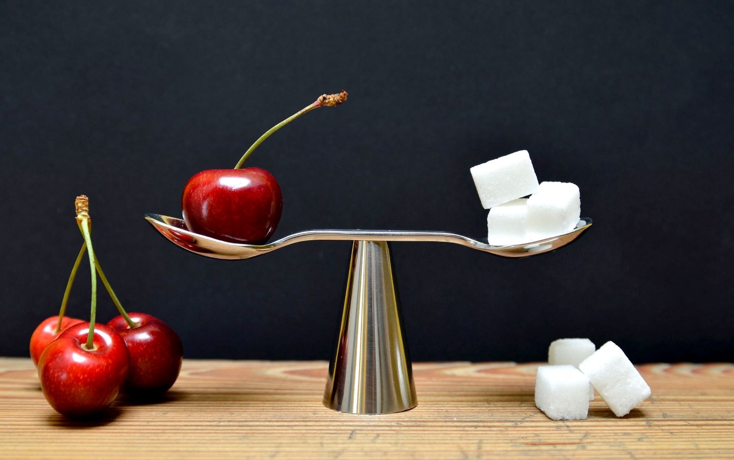 A scale balancing an apple with sugar cubes