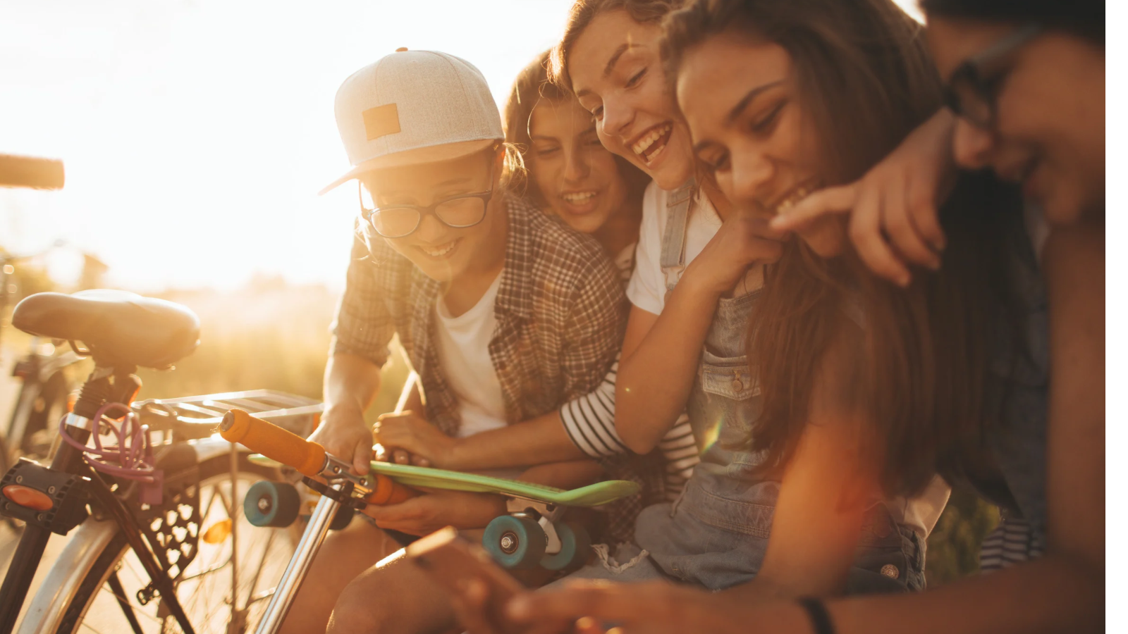 group of teenagers hanging out together laughing at their phones