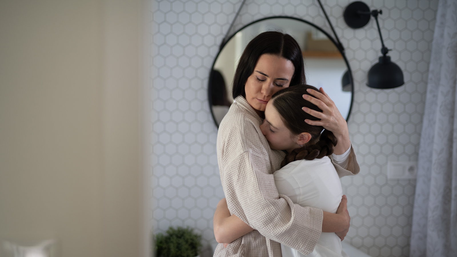 mother and daughter hug in home bathroom