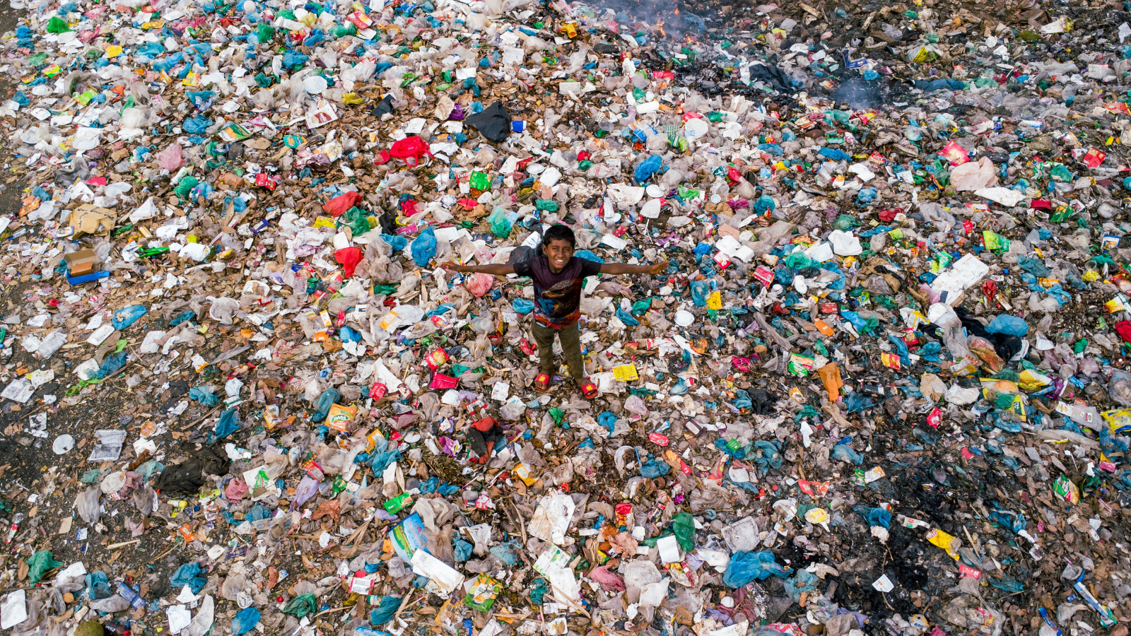 boy standing in field of plastic garbage