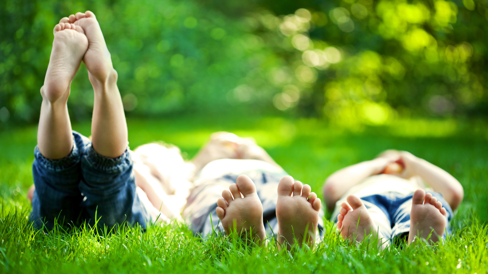 Group of happy children lying on green grass outdoors in spring park