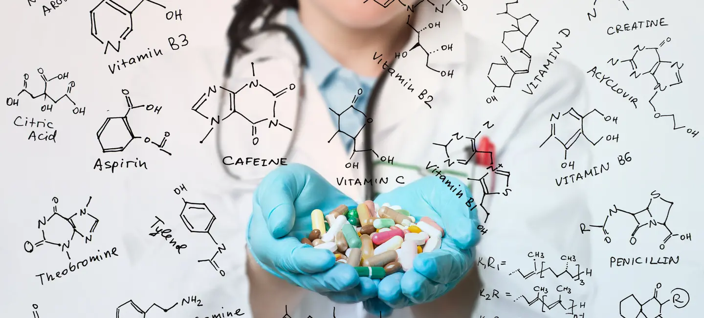 Healthcare worker wit hands full of pills surrounded by formula of vitamines and food additives