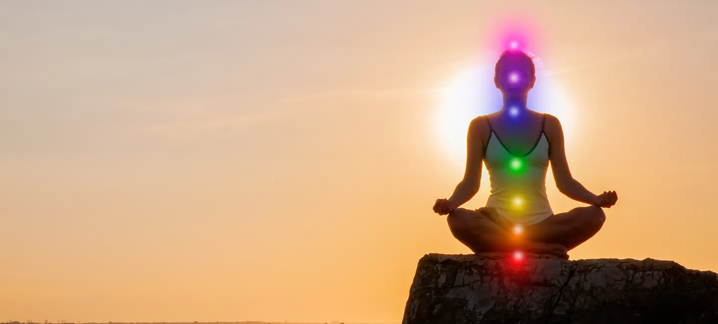 Woman meditating with glowing seven chakras