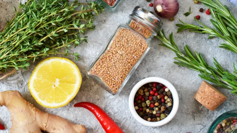 Mix of spices: rosemary, thyme, pepper, garlic, ginger, lemon on a concrete background