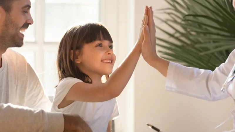 Healthy happy child girl giving high five to female caring doctor
