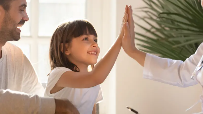 Healthy happy child girl giving high five to female caring doctor Healthy happy child girl giving high five to female caring doctor