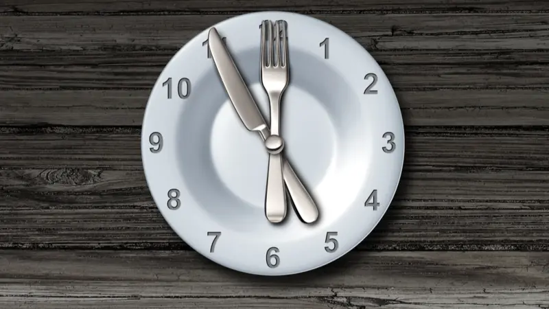 Intermittent fasting and calorie restriction promoting healthy benefits with a clock icon on a plate with knife and fork