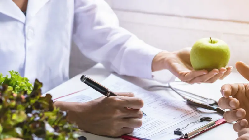 Nutritionist giving consultation to patient with healthy fruit and vegetable