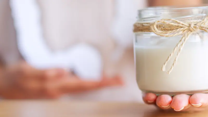 Female hand is holding jar with natural organic yogurt with bifidobacteria