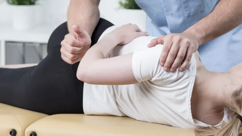 Physiotherapist is rehabilitating young woman back in medical office