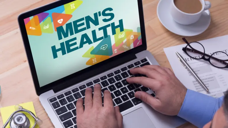 Doctor working on a laptop and MEN'S HEALTH on his screen