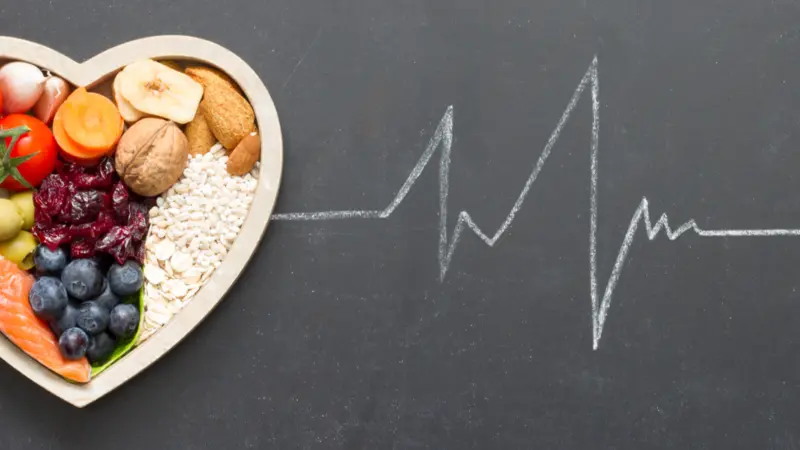 Healthy food in heart and cardiograph on blackboard