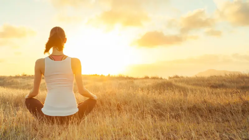 Woman meditating against a beautiful sunset. Woman meditating against a beautiful sunset.
