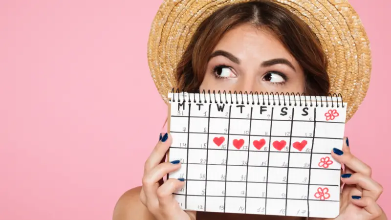 girl in summer hat hiding behind a periods calendar girl in summer hat hiding behind a periods calendar