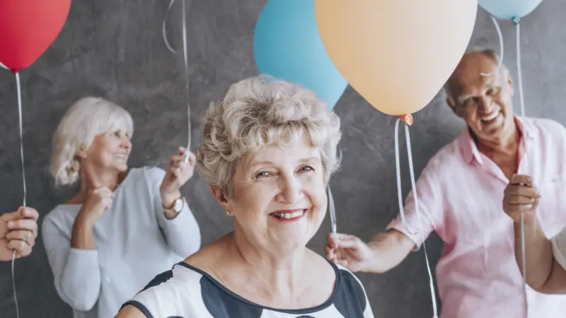 Happy senior people with colorful balloons celebrating their friend's birthday