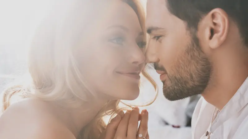 young couple bonding and smiling while sitting in the bedroom