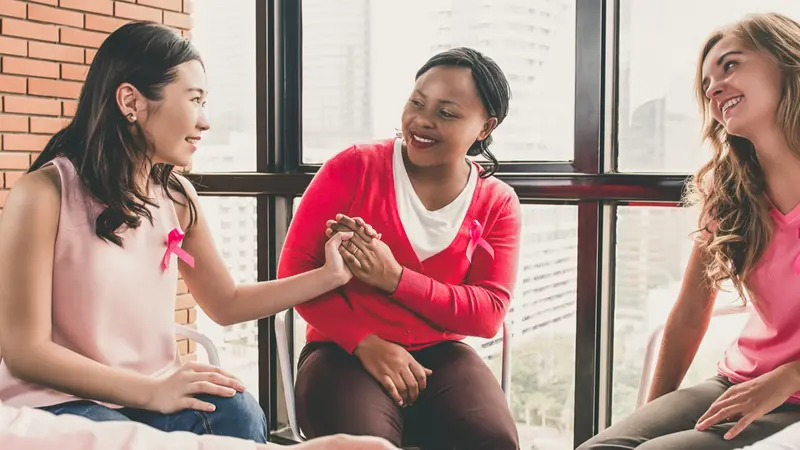 women wearing pink color clothes sitting in circle talking and meeting for breast cancer awareness campaign