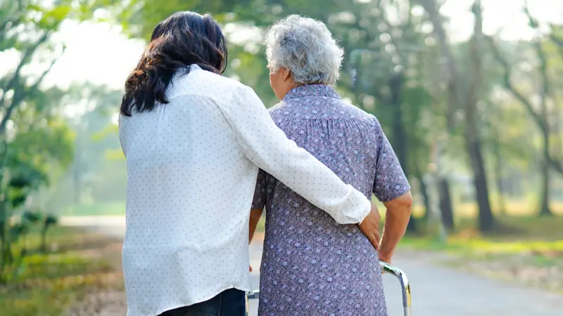 Helping senior woman use walker while walking at park Helping senior woman use walker while walking at park