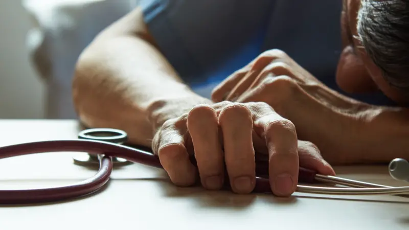 burnout surgeon feeling tired in medical office with a stethoscope on the table burnout surgeon feeling tired in medical office with a stethoscope on the table