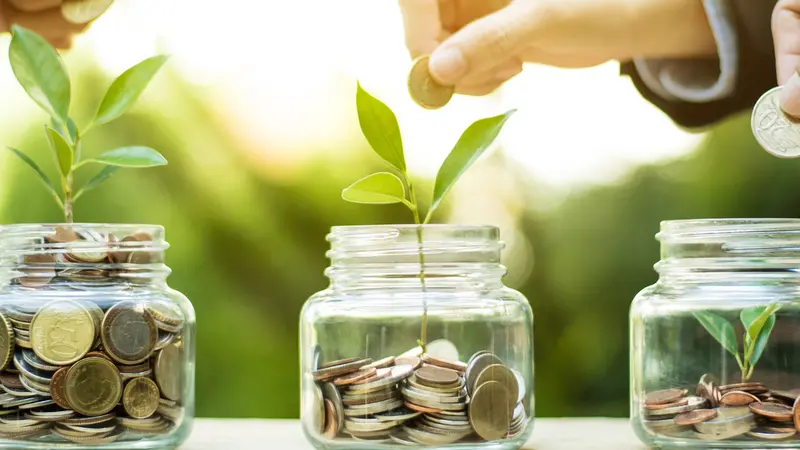 hands putting money (coin) into the glass jar 