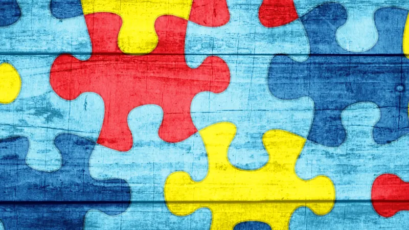 A colorful autism awareness puzzle background with wood texture illustration.