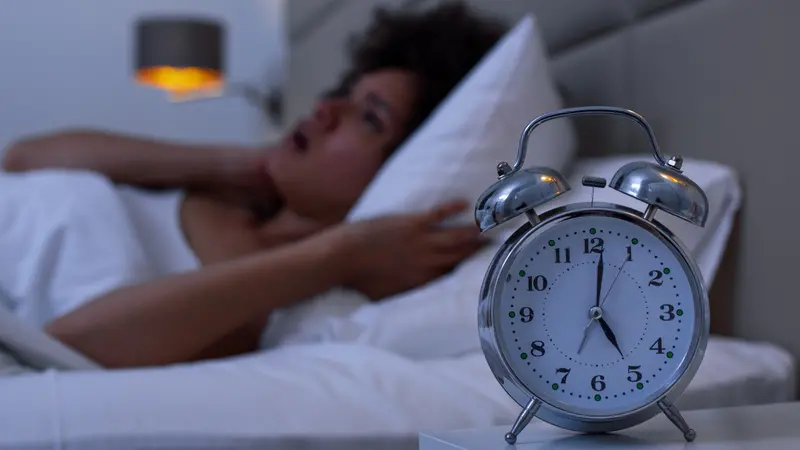 Woman with insomnia lying in bed with open eyes