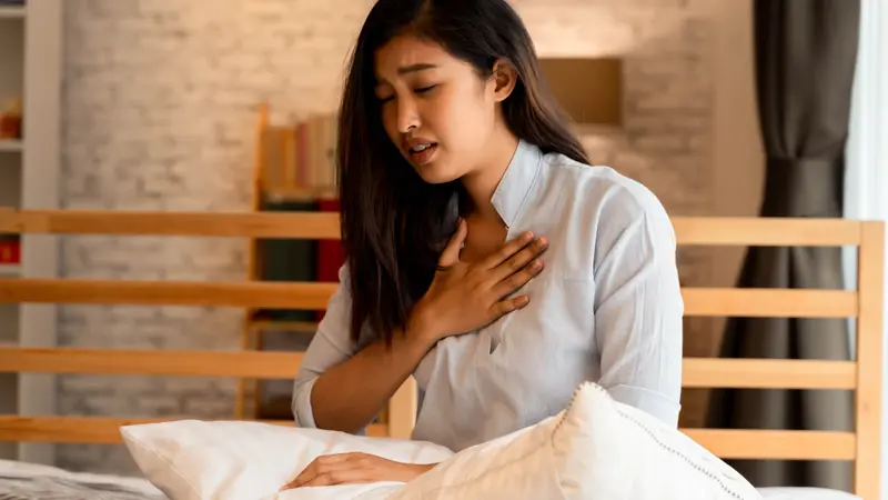  woman having difficulty breathing in bedroom