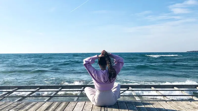 women sitting on dock facing the ocean
