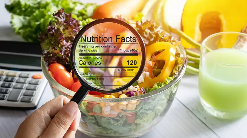 hand use the magnifying glass to zoom in to see the details of the nutrition facts from food , salad bowl