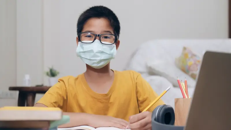 Boy wearing face masks online study homeshcooling at home.