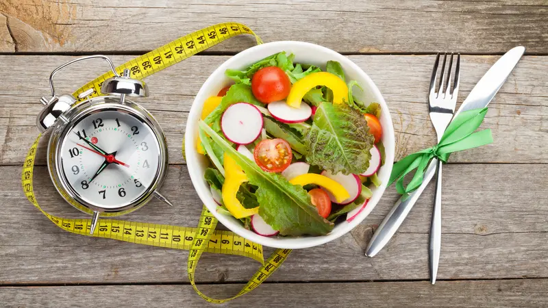 Fresh healthy salad and measuring tape on wooden table