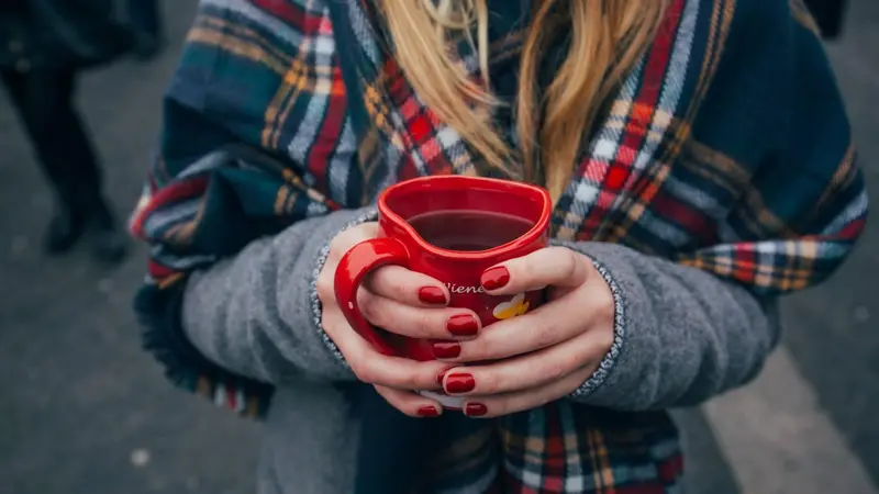 woman's hands holding red mug