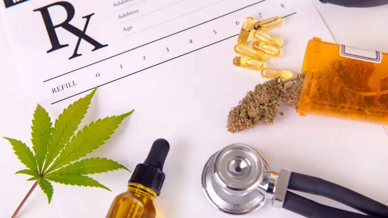 Assorted cannabis products, pills and cbd oil over medical prescription sheet - medical marijuana concept