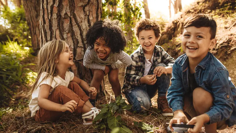 kids sitting together in forest and looking at camera