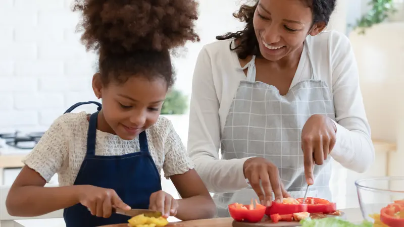 african american mother and tween daughter prepare vegan food