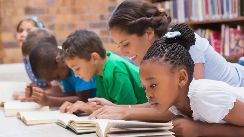 pupils and teacher lying on floor in library at the elementary school